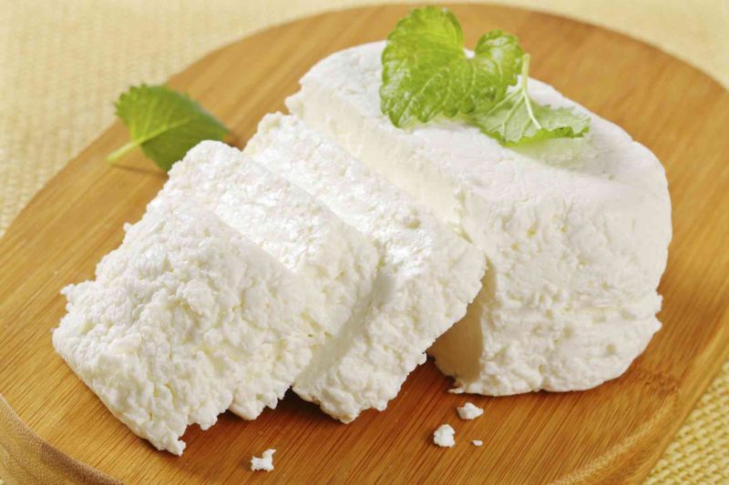 sliced ricotta cheese with a fresh mint on a wooden cutting board